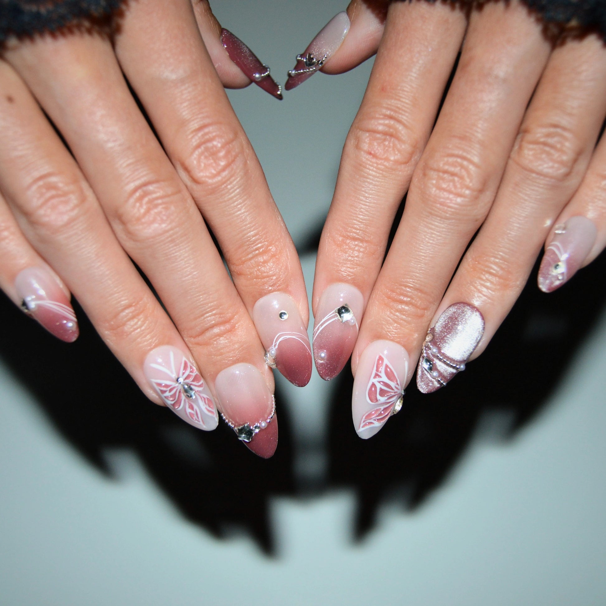 Ongles press-on Butterfly portés, faits main en gel et acrylique, nail art papillon rose, strass et dégradé brillant.