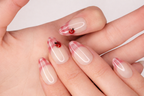 Gros plan sur les détails avec faux ongle press-on coccinelle peinte sur base blanc crème — design Lady Bug fait main — Mimi Press-On