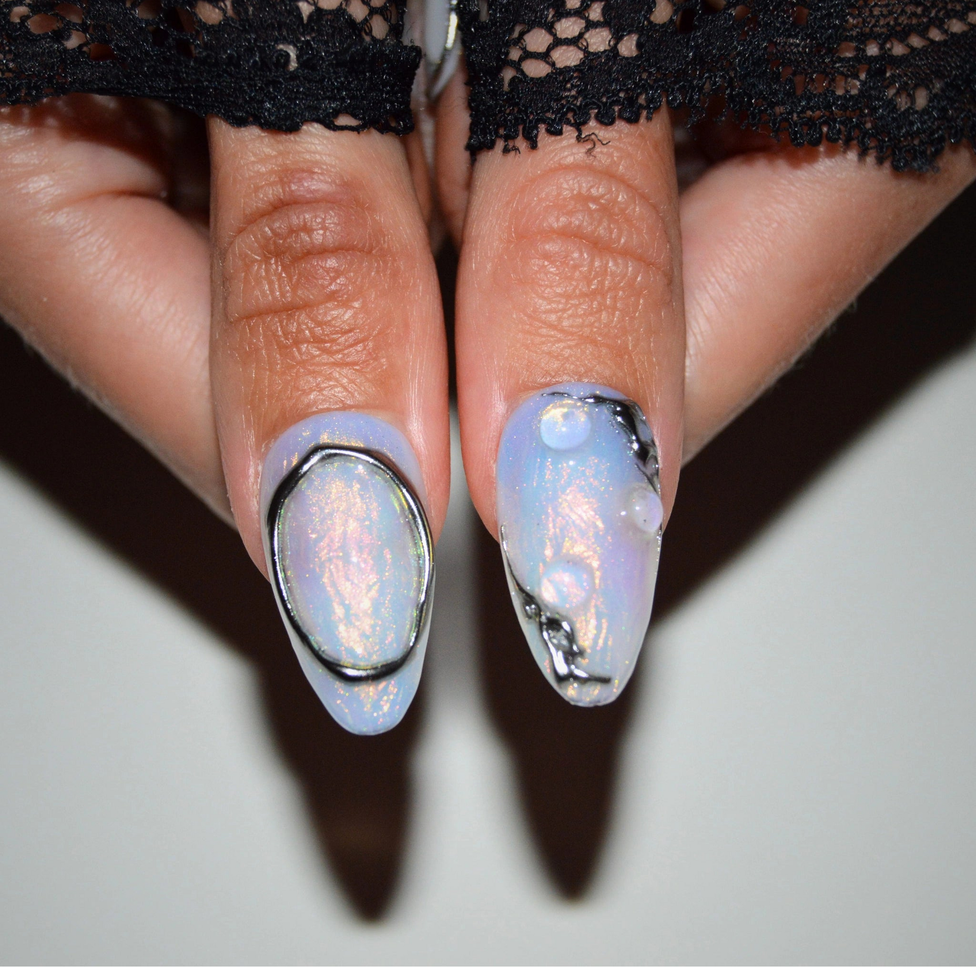 Gros plan sur deux ongles Liquid Metal, effets opale irisée et métal liquide sculpté, press-on faits main gel et acrylique.