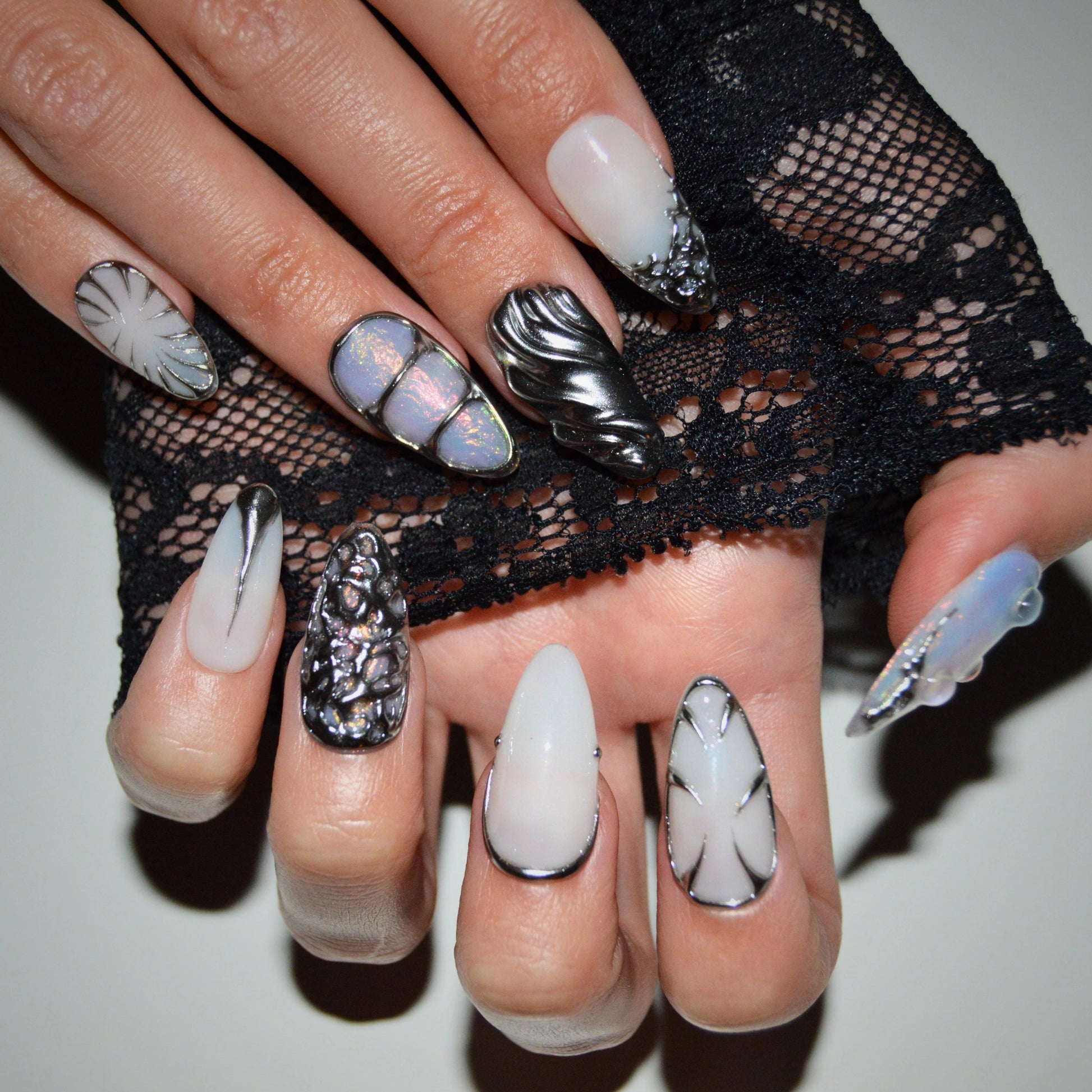 Pose sur les deux mains du set Liquid Metal, mélange d’effets métal liquide, opale holographique et lignes chromées, press-on faits main gel et acrylique.