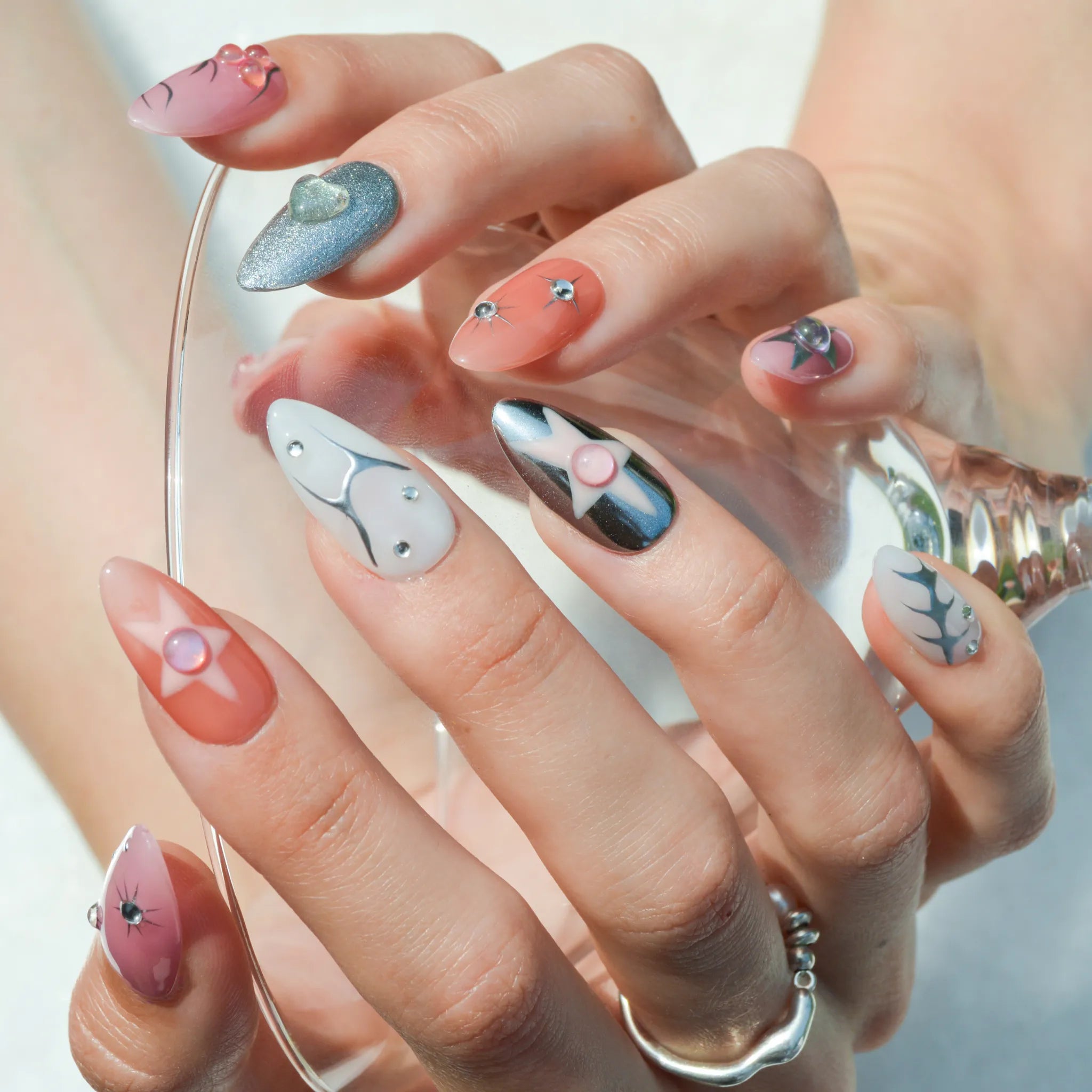 Manucure Metallic Muse avec designs 3D, étoiles, chrome argent et dégradés rosés.