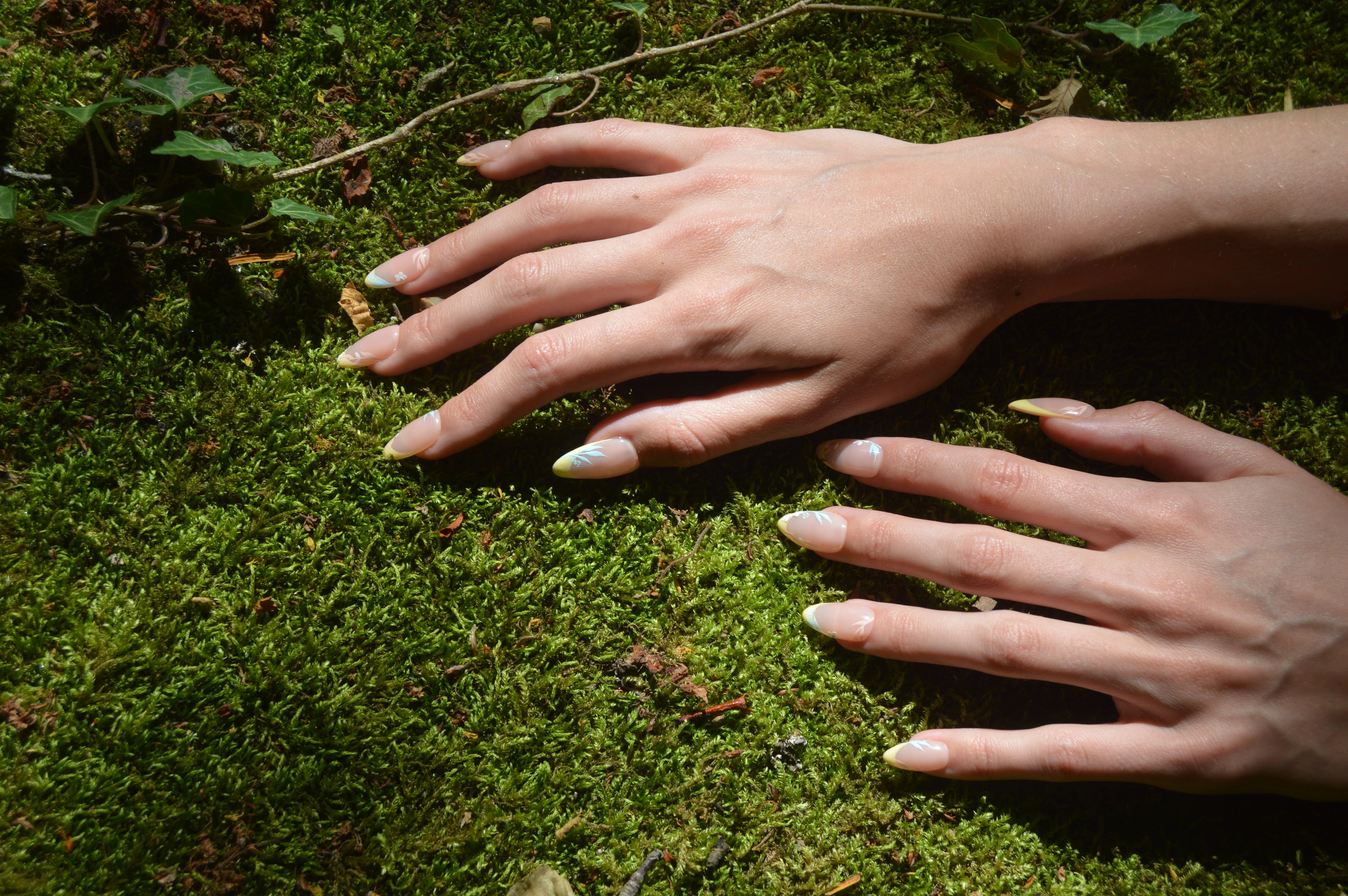 Faux ongles Secret Garden posés sur un tapis de mousse verte, style floral et jaune pastel inspiré du jardin.