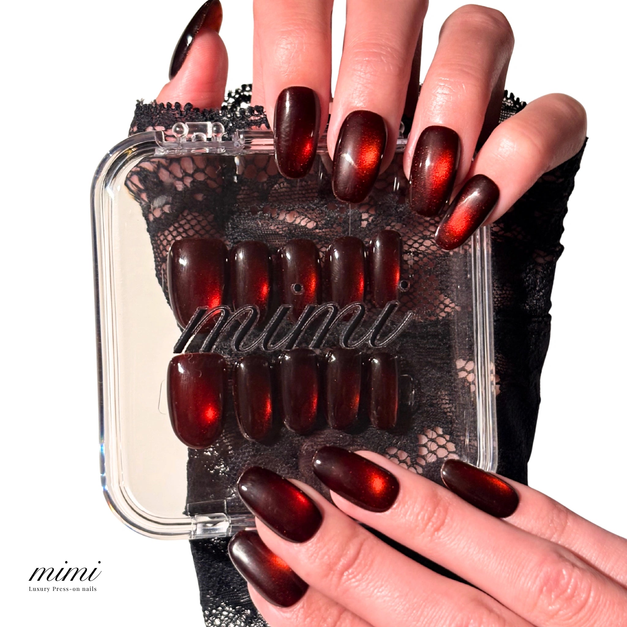Boîte Mimi contenant des press-on nails faits main en gel et acrylique, design cat eye rouge métallisé, présentation avec main tenant l’étui.