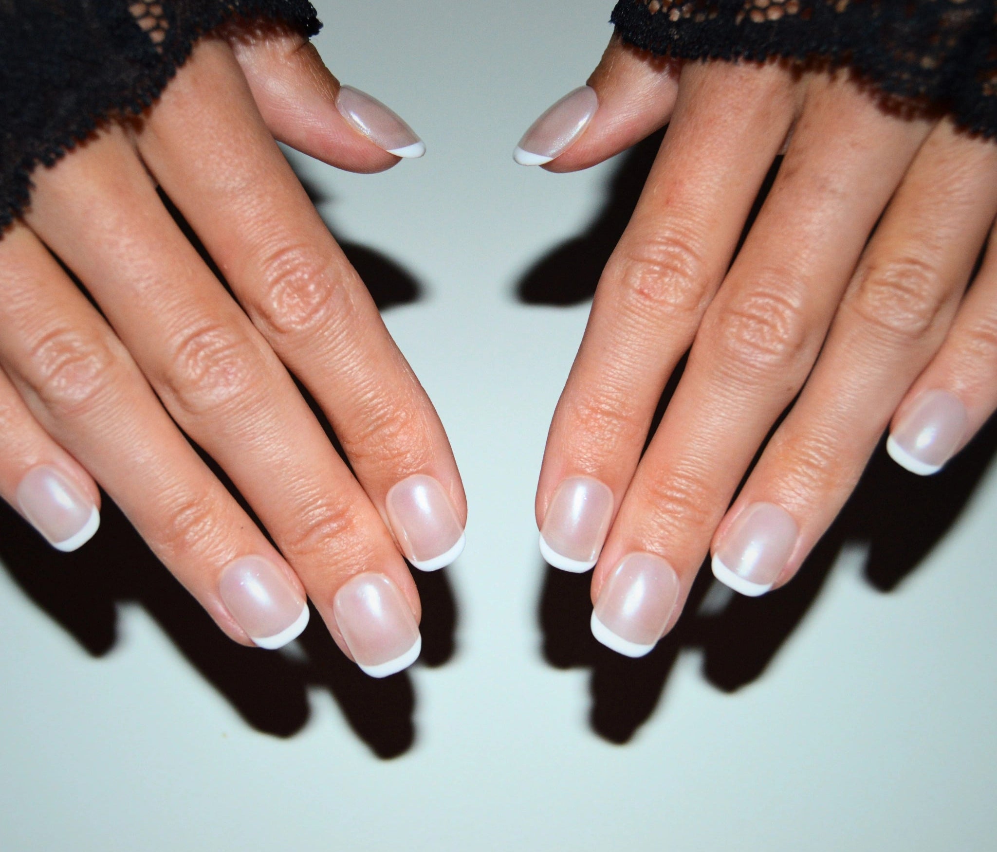 French manucure carrée courte en press-on, finition gel et acrylique, mains posées à plat.