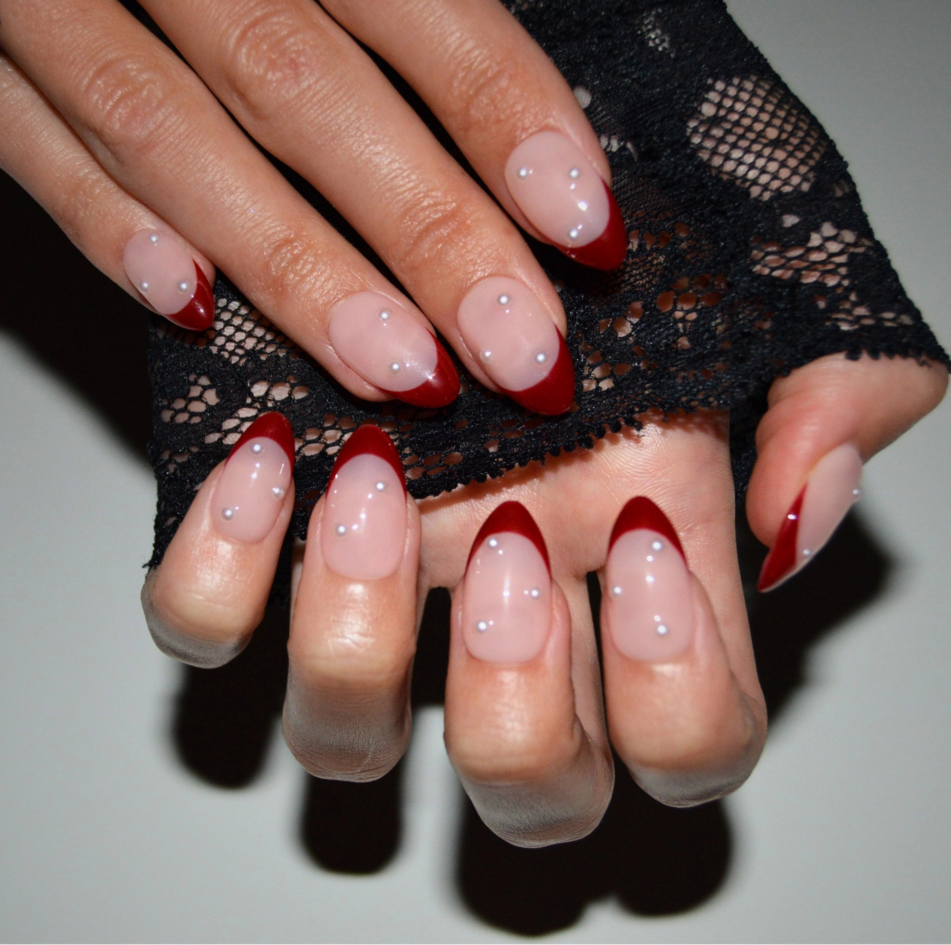 Détails du set Holly Ruby porté, french rouge perlée et dentelle noire en arrière-plan, press-on nails Mimi faits main.