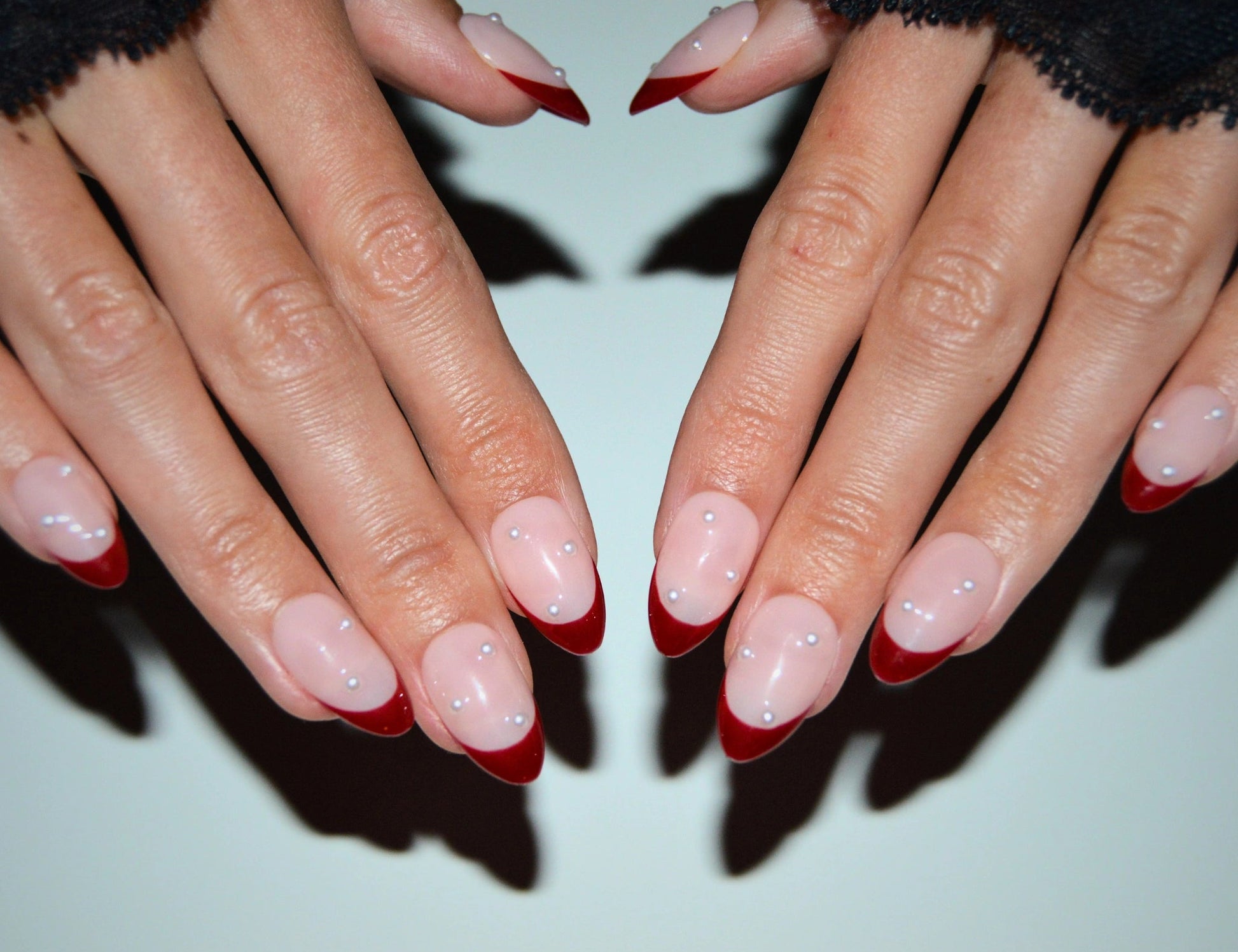 Ongles Holly Ruby portés, french rouge élégante avec perles, pose symétrique des mains, press-on nails réutilisables Mimi.