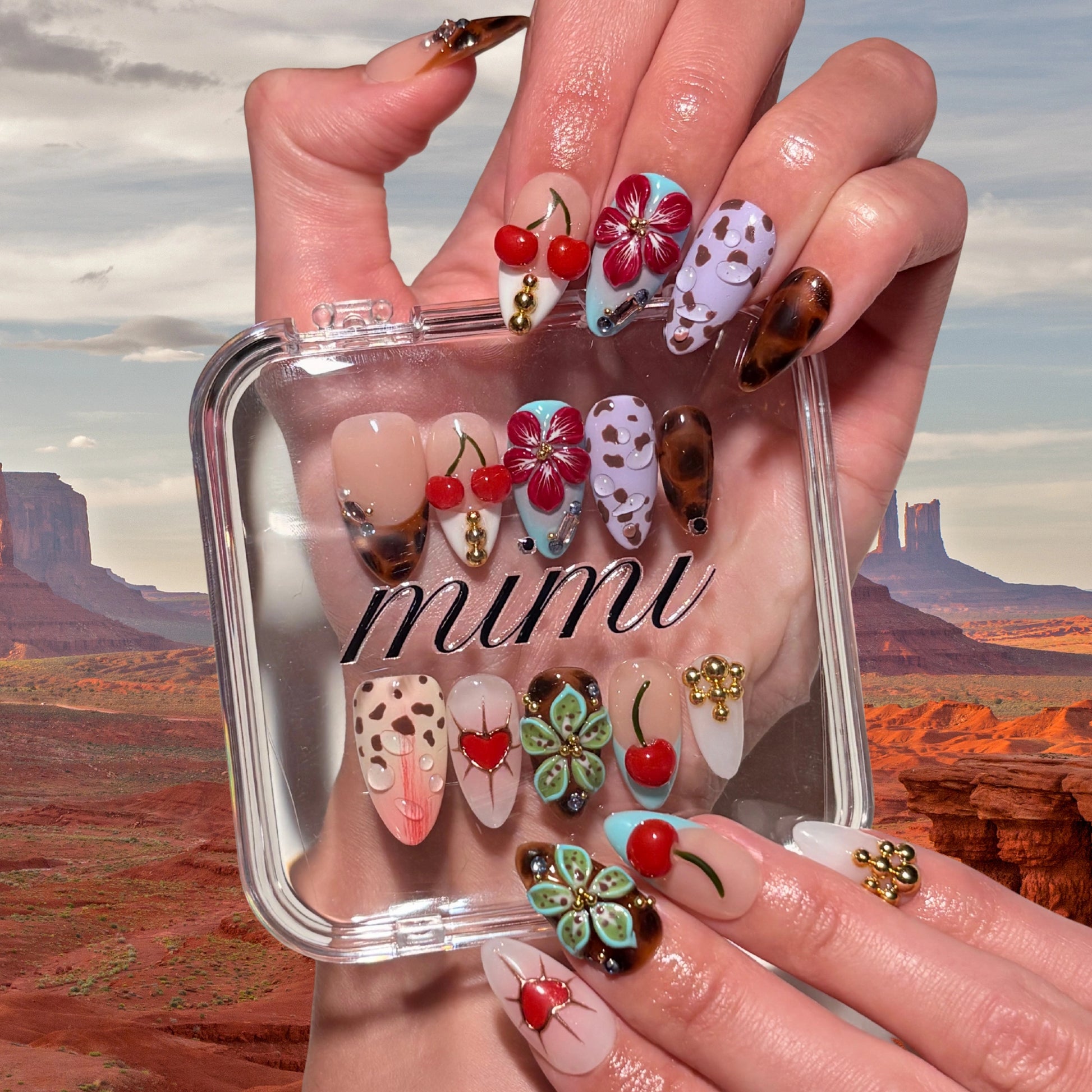 Boîte du set Trip to Vegas Mimi, press-on nails faits main en gel et acrylique haut de gamme, motifs 3D cerises, fleurs, léopard et écaille, présentation artistique désert.