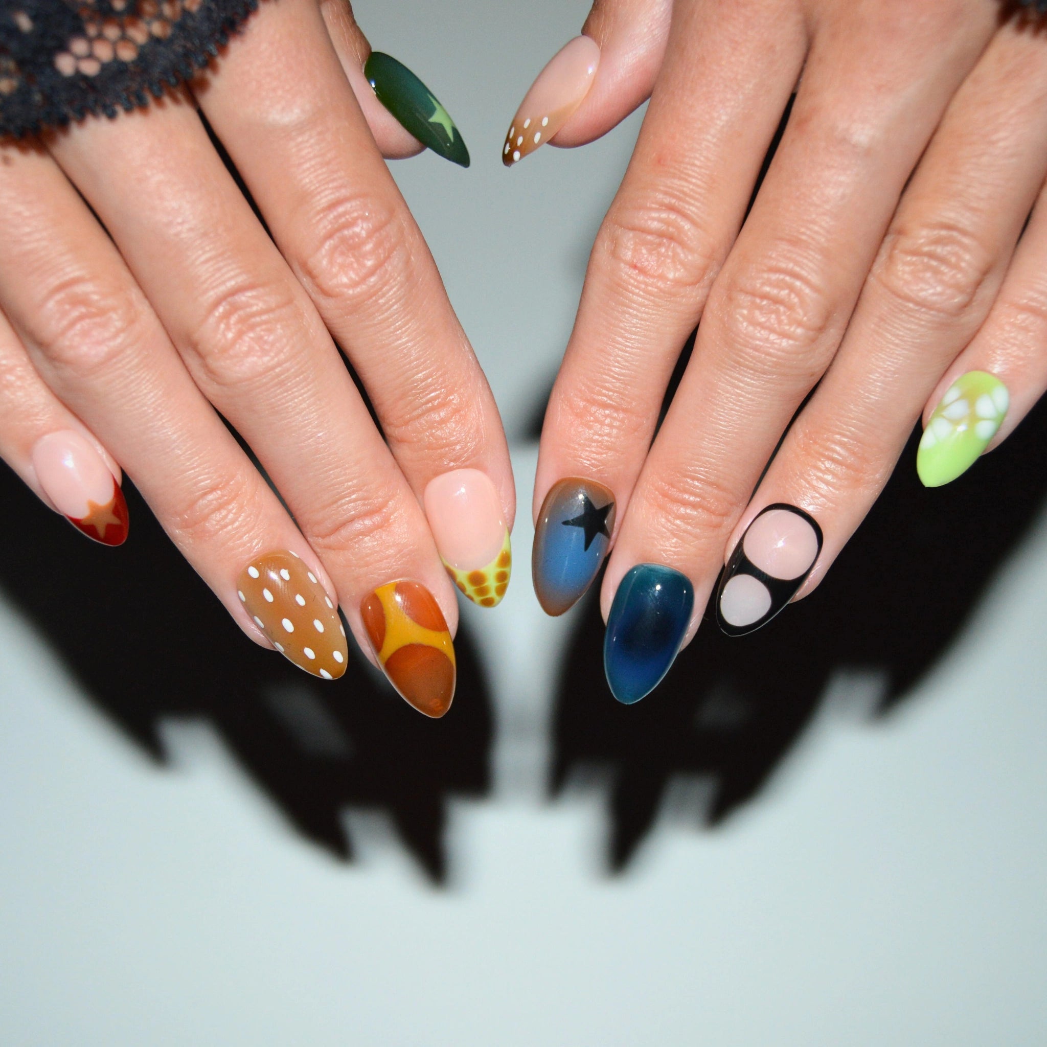 Press-on nails Wonderfall portés, motifs automnaux multicolores avec étoiles, pois et dégradés, rendu artistique Mimi France.