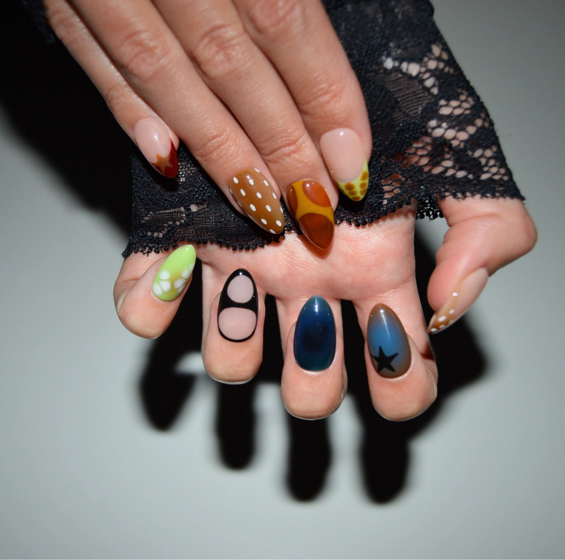 Ongles Wonderfall portés, designs variés inspirés de l’automne avec motifs graphiques, vue artistique avec dentelle noire, press-on nails Mimi.